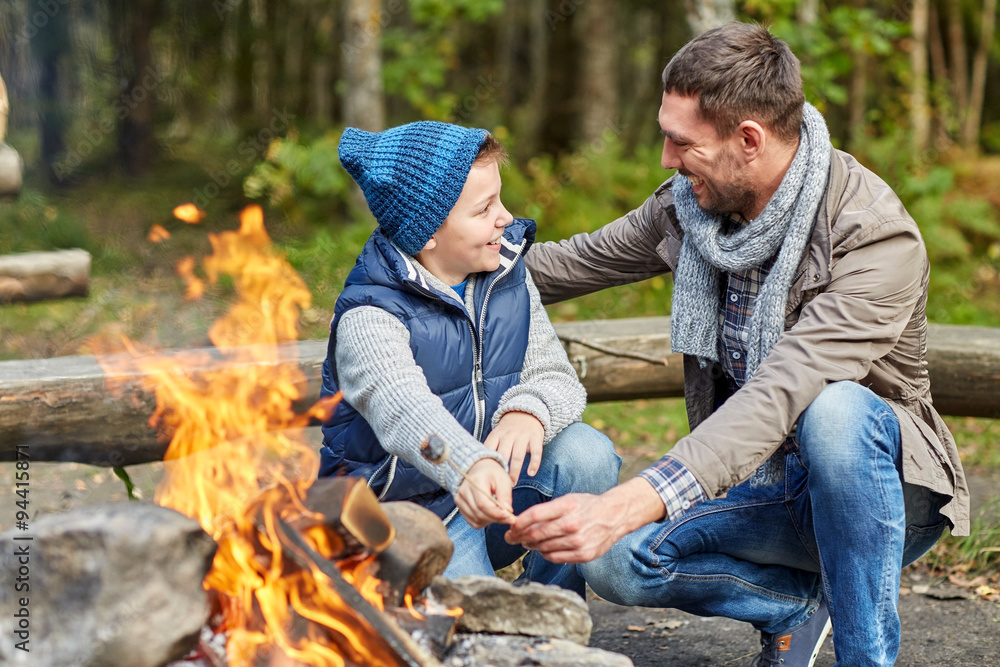 father and son roasting marshmallow over campfire father and son roasting marshmallow over campfire