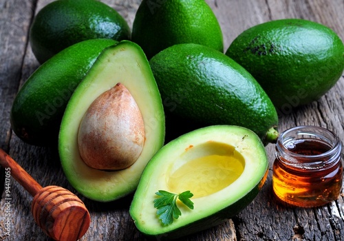 Fresh avocado with olive oil and honey on wooden background photo