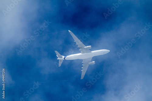 Airplane between clouds on a blue sky