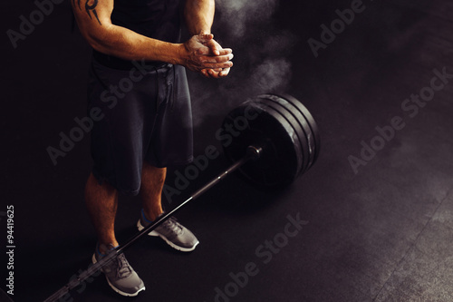 Athlete clapping hands with talc before deadlift barbells workout photo