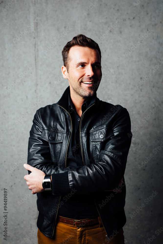 Happy man in leather jacket against concrete wall Happy man in leather jacket against concrete wall