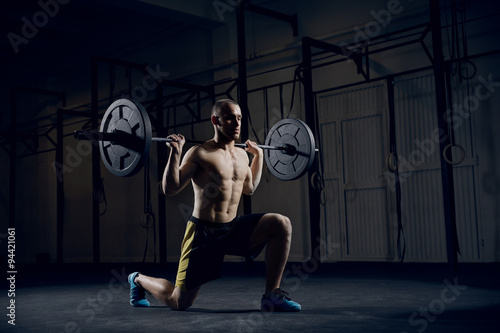 Young athlere training lunges with barbells