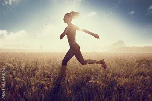 Young fit woman running during sunny morning