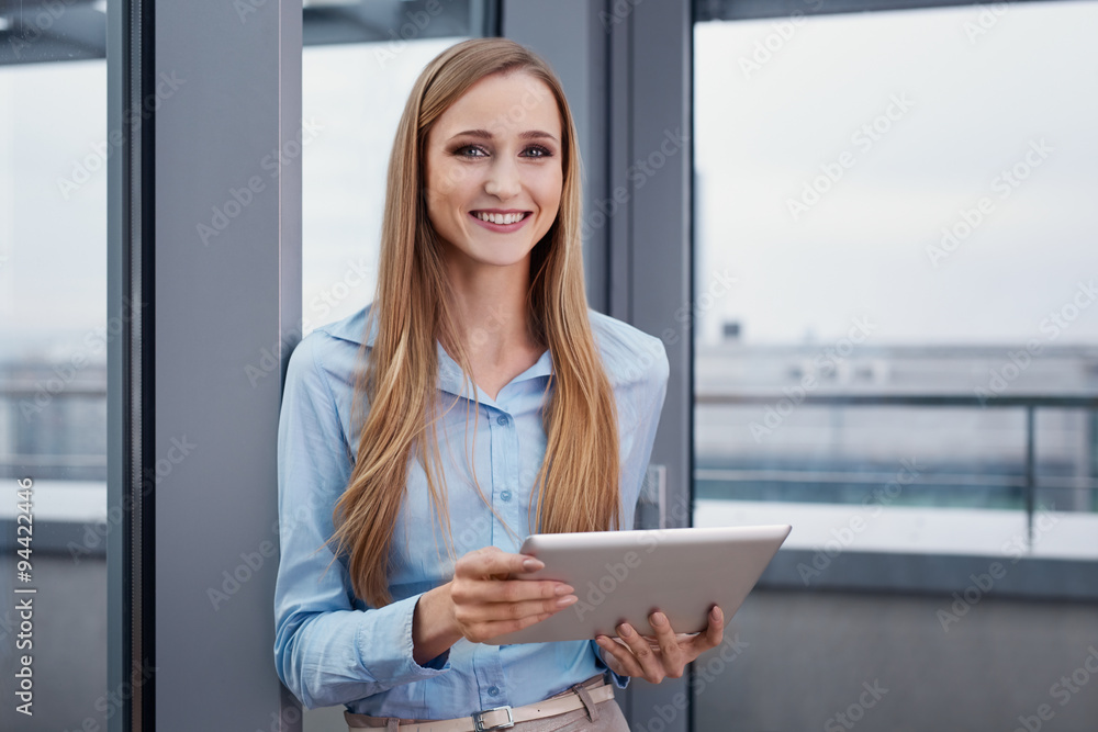 Cheerful woman at office standing with digital tablet