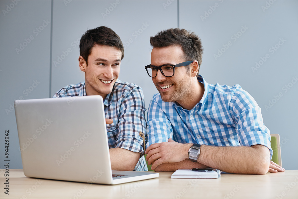 Two web designers working on laptop at office Two web designers working on laptop at office