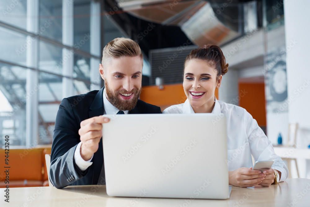 Two happy business people working on laptop at office Two happy business people working on laptop at office