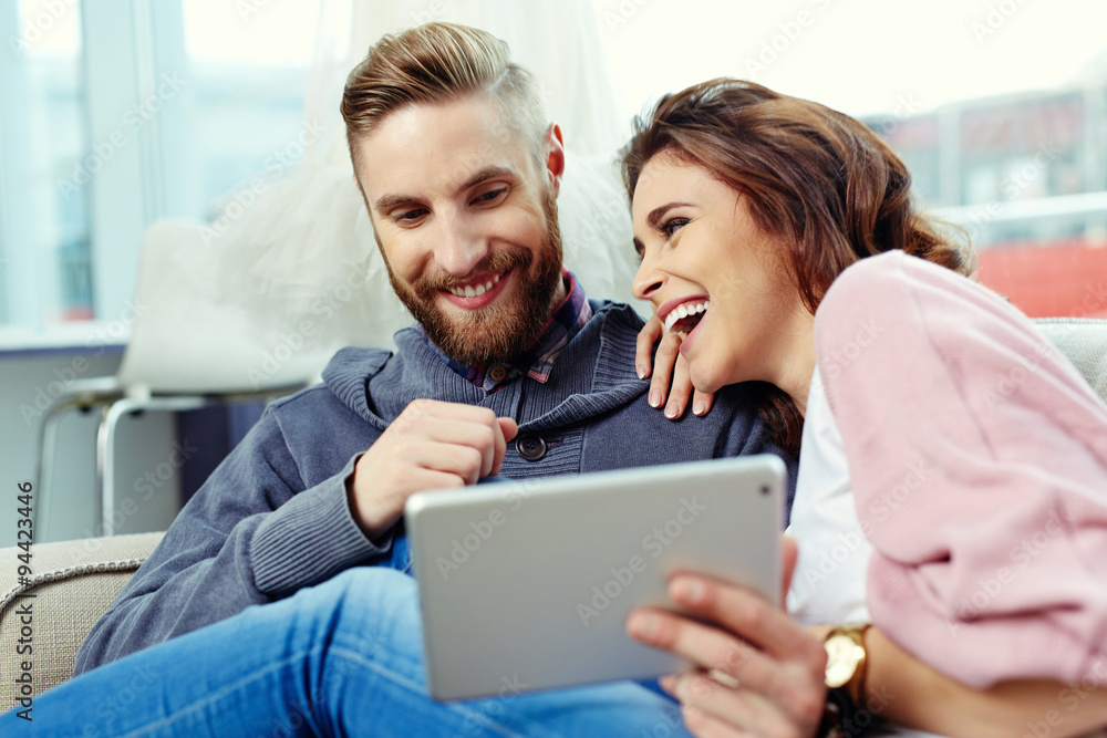 Happy couple using tablet and laughing Happy couple using tablet and laughing