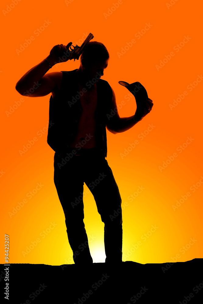 silhouette of a cowboy with a pistol by head hat in hand