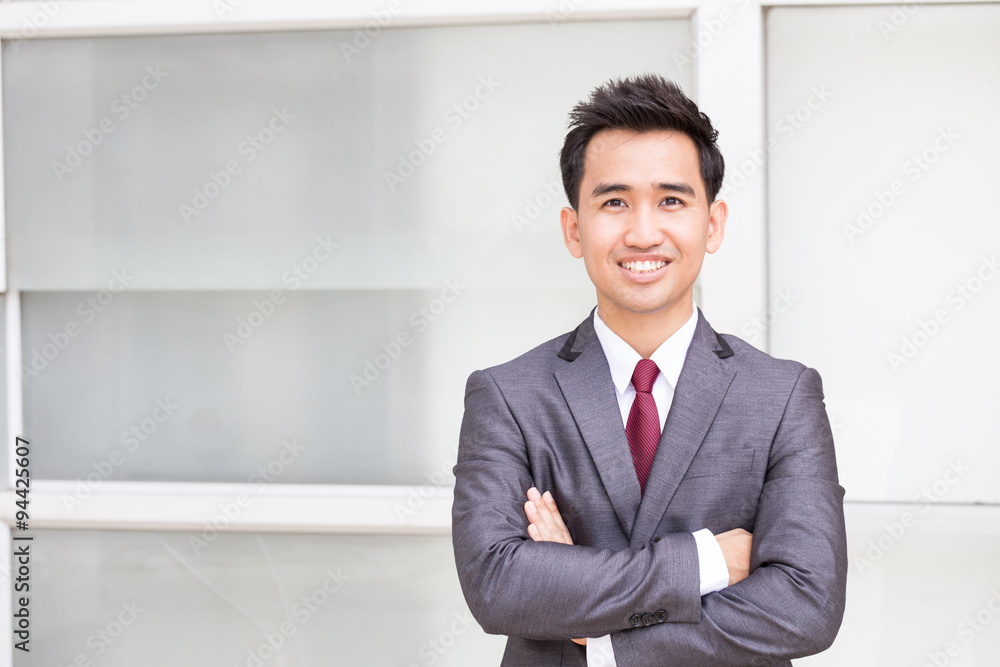 Asian businessman standing arms crossed and smiling Asian businessman standing arms crossed and smiling