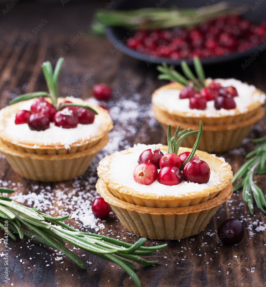Tartlets of pastry with cream and fresh berries ripe cranberries, rosemary leaves