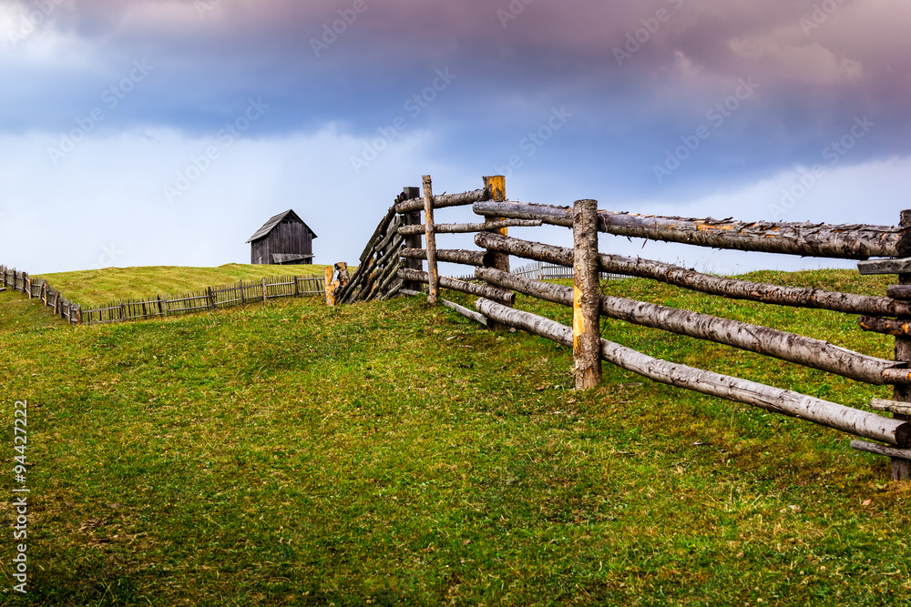 Field of green with wooden house on the hill