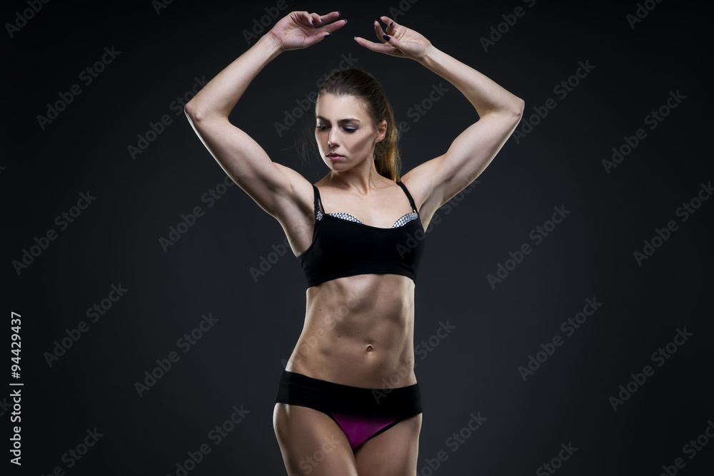 Muscular attractive fitness woman on gray background in studio