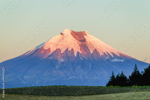 Experience the breathtaking beauty of Cotopaxi Volcano in Ecuador as the golden hues of the sunset light up the majestic landscape.
