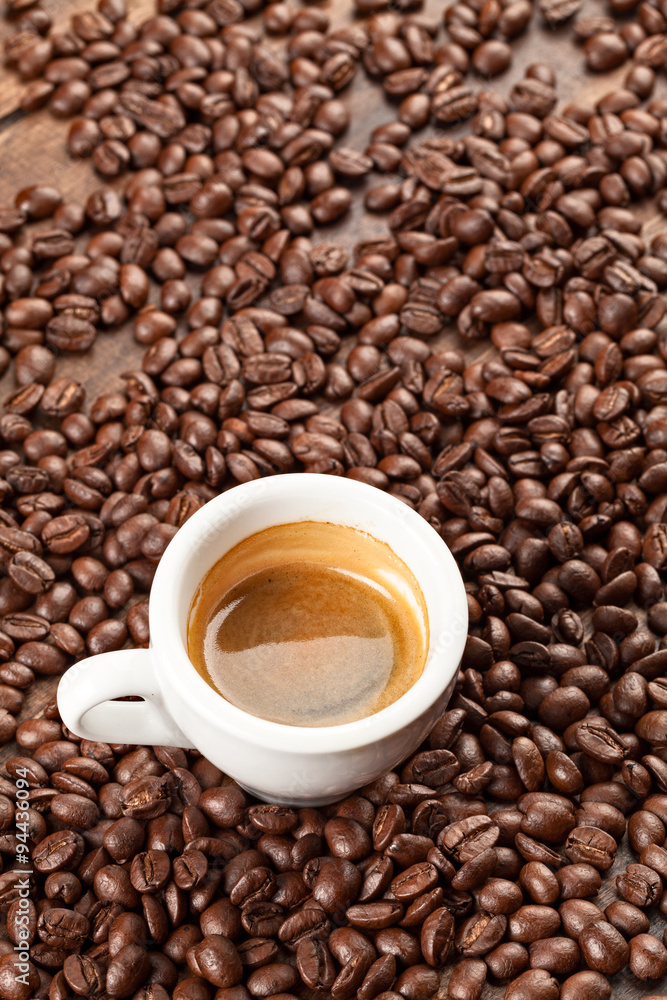 A petite espresso cup delicately placed amidst aromatic roasted coffee beans creating a visually captivating scene that fosters an atmosphere conducive to scholarly pursuits
