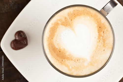 A steaming latte in a white mug, topped with frothy milk and creamer swirls, ready to be enjoyed on a cozy morning.
