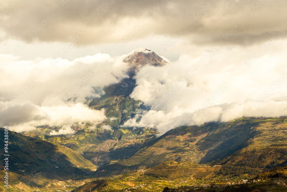 A breathtaking view of the misty sky above Banos, Ecuador, with a majestic mountain and volcano in the background.