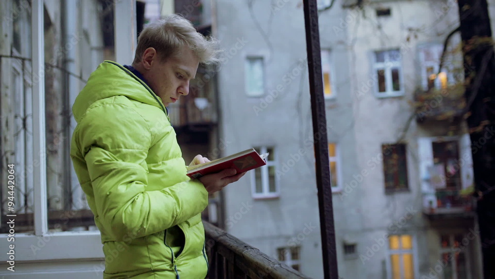 Boy standing on the balcony and reading book
Boy standing on the balcony and reading book