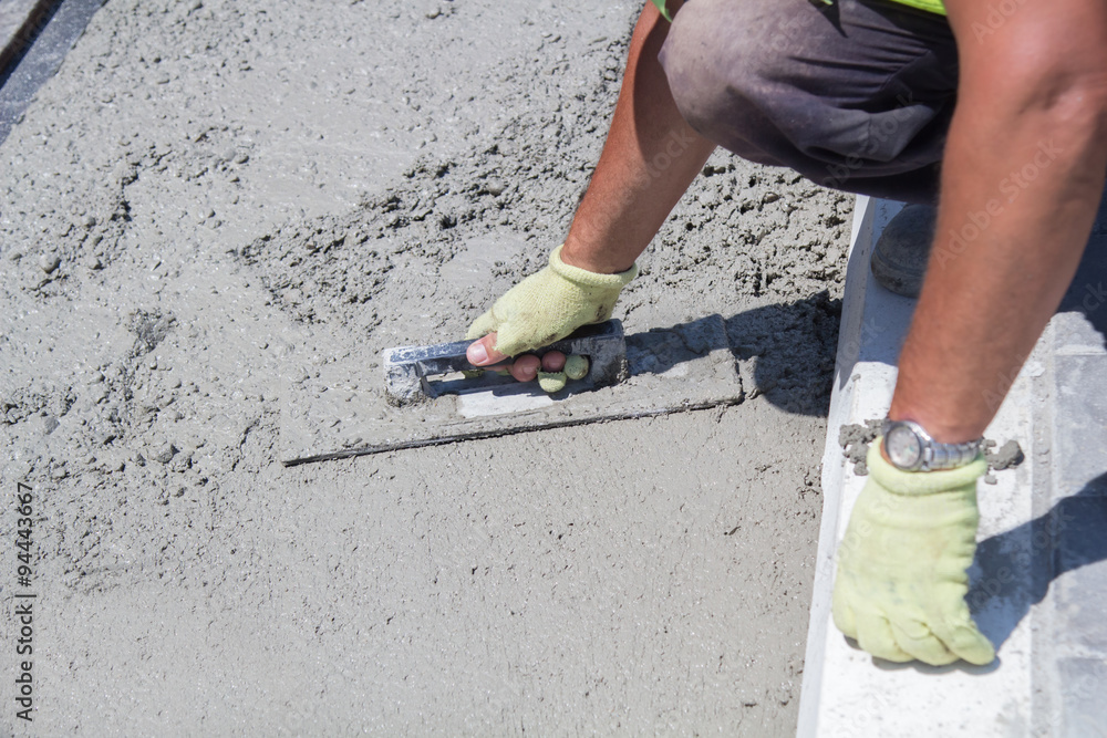 Construction worker leveling concrete pavement.