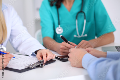 Doctors and patient are discussing something, just hands at the table