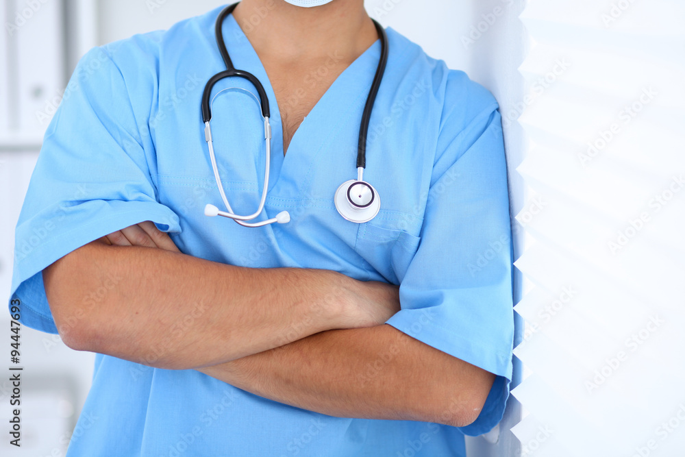 Portrait of unknown male surgeon doctor standing near the wall in hospital office Portrait of unknown male surgeon doctor standing near the wall in hospital office