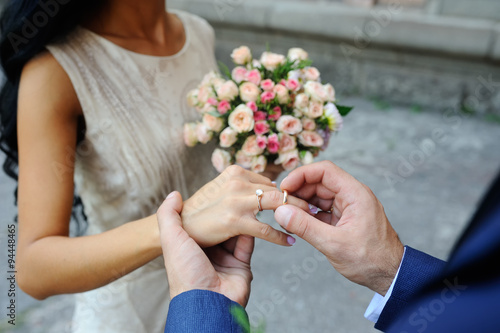Groom wears a wedding ring a bride