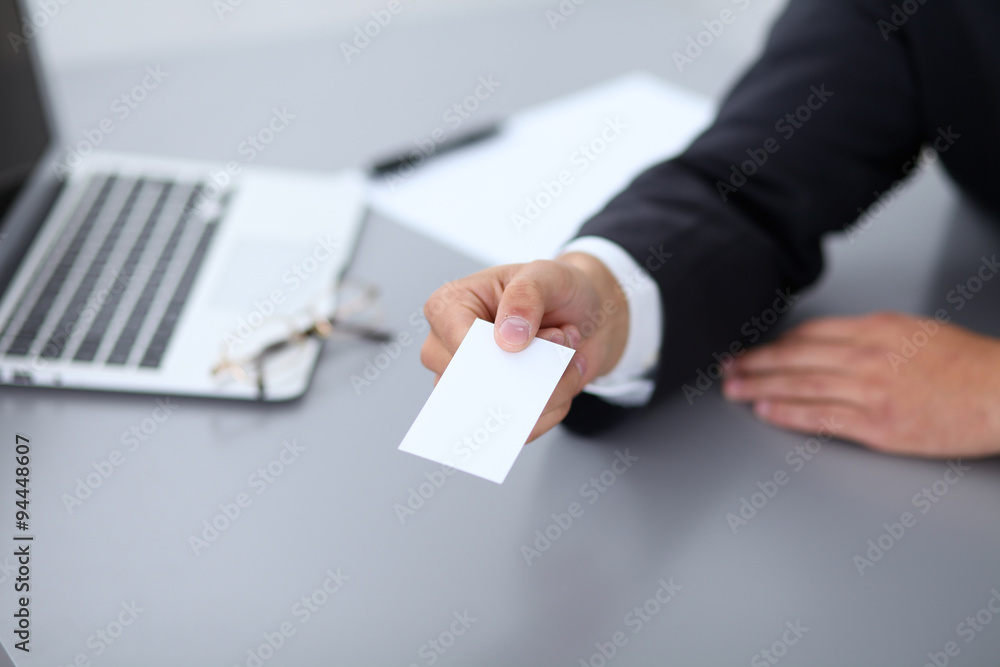 Close-up of businessman giving a business card, sitting at the table Close-up of businessman giving a business card, sitting at the table
