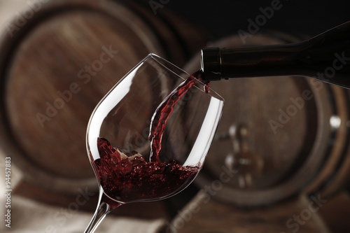 Pouring red wine from bottle into glass, black and white retro stylization