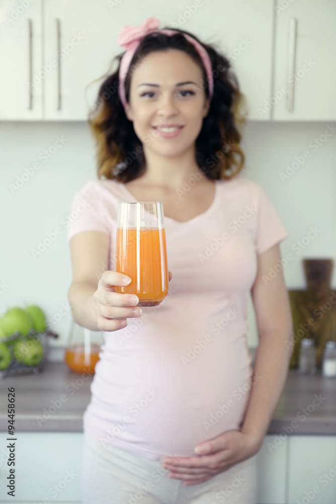 Young happy pregnant woman with glass of juice on the kitchen Young happy pregnant woman with glass of juice on the kitchen