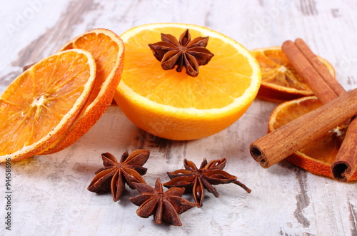 Dried and fresh orange with spices on old wooden background