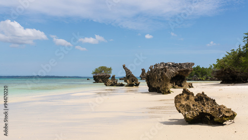 Pristine white tropical beach with rocks, blue sea and lush vege photo