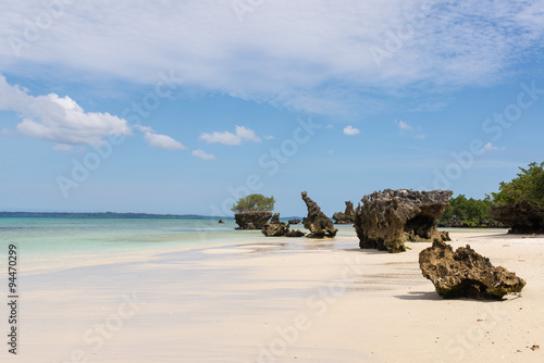 Pristine white tropical beach with rocks, blue sea and lush vege photo