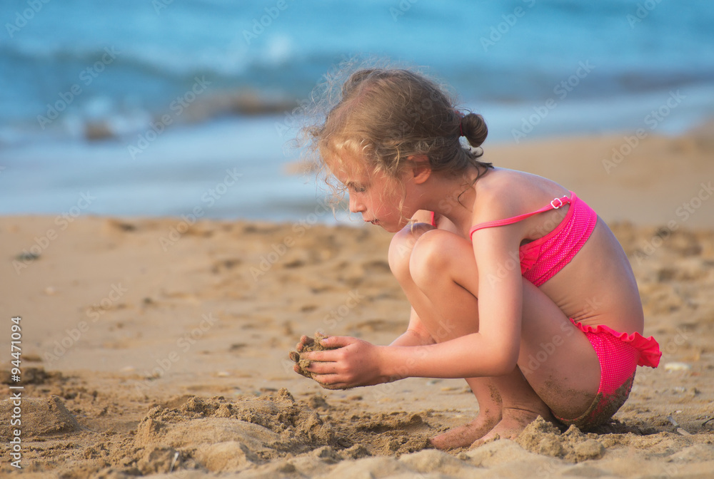 Little girl playing with sand on the beach. Little girl playing with sand on the beach.