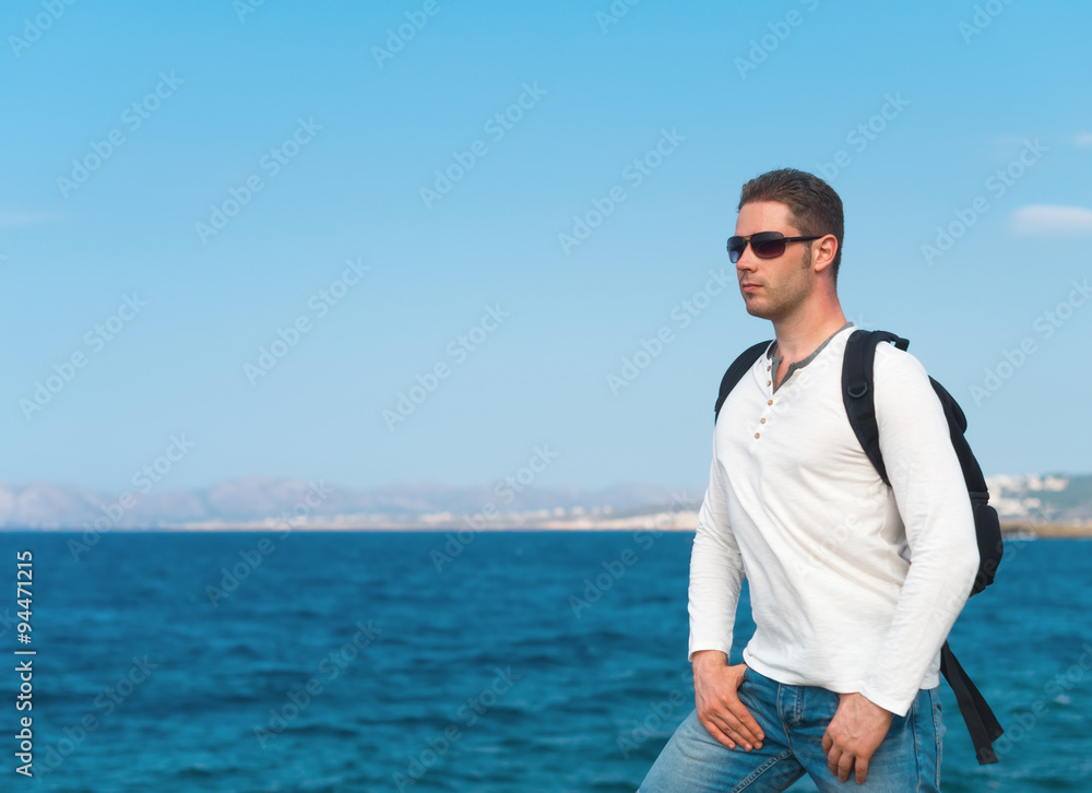 Male tourist with backpack standing near the sea. Male tourist with backpack standing near the sea.
