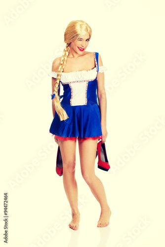 Woman in Bavarian dress holding her shoes.