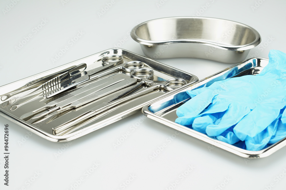 Medical instruments and blue gloves in a stainless steel tray Medical instruments and blue gloves in a stainless steel tray