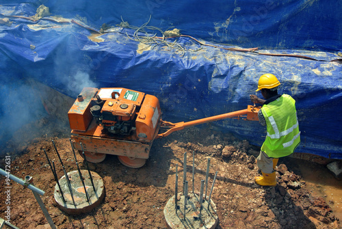 Construction workers using baby roller compactor