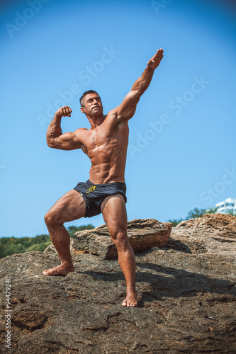 Man Athlete on a rock by the sea against the sky
