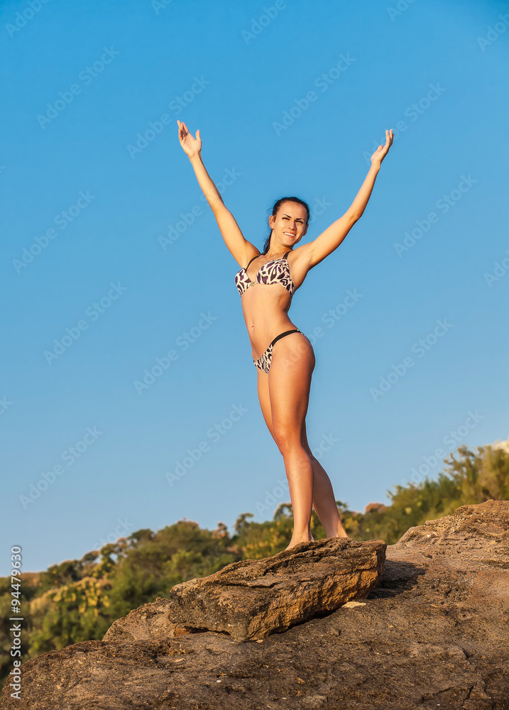Women Athlete on a rock by the sea against the sky Women Athlete on a rock by the sea against the sky