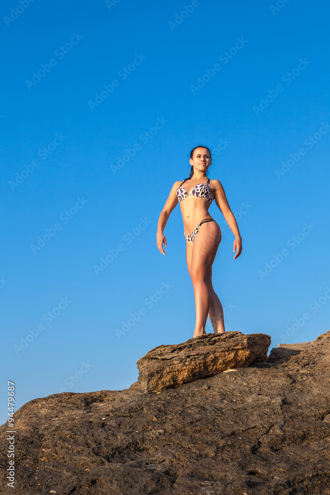 Women Athlete on a rock by the sea against the sky