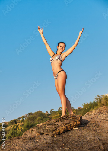 Women Athlete on a rock by the sea against the sky