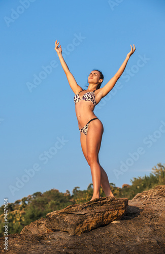 Women Athlete on a rock by the sea against the sky