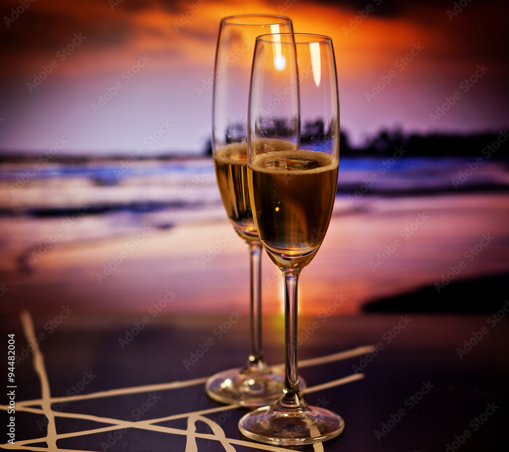 Champagne glasses on tropical beach at sunset - exotic New Year