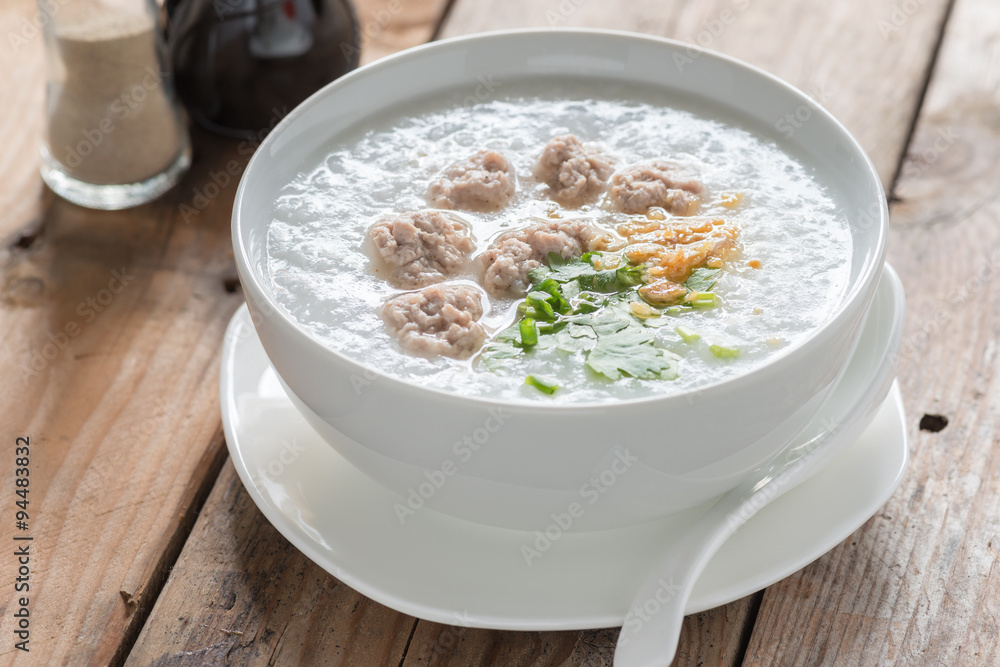 Traditional thai congee with minced pork in white bowl.