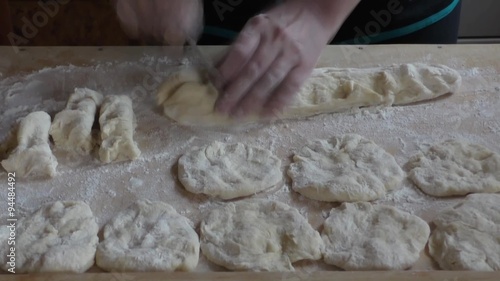 A woman kneads dough on a wooden cutting board   photo