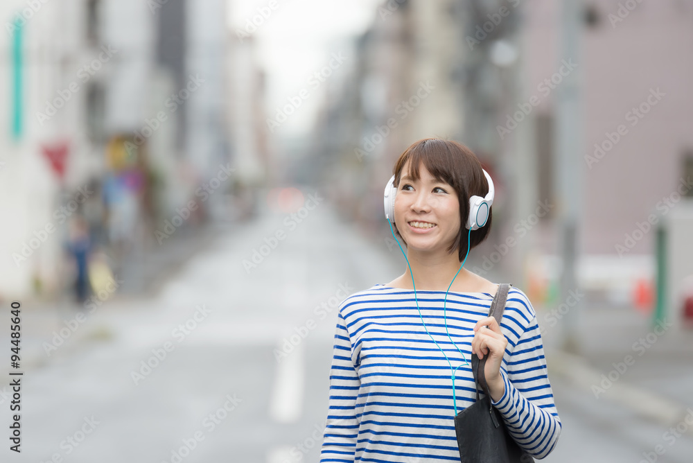 Fototapeta premium ヘッドホンで音楽を聞きながら歩く女性