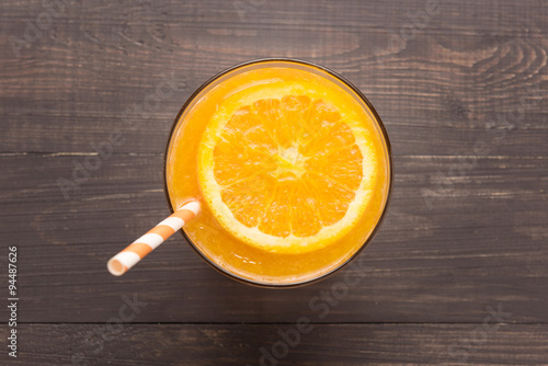 Fresh orange juice in glass on wooden background