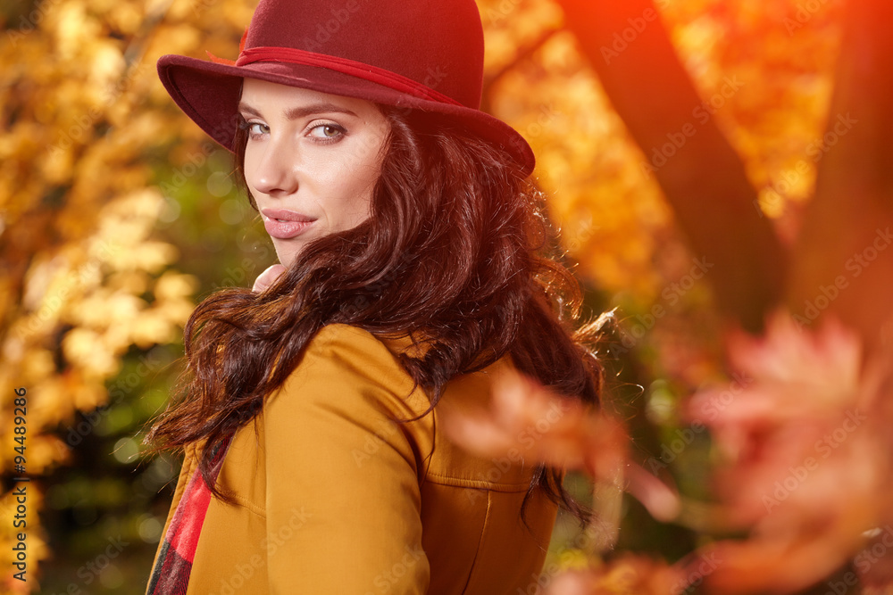 Beautiful elegant woman standing in a park in autumn Beautiful elegant woman standing in a park in autumn