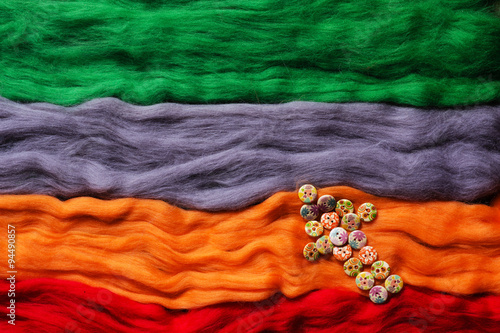 Multi-colored strands of wool felting and arrow made from buttons