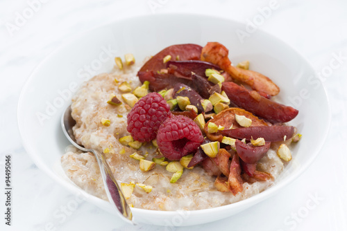 oatmeal with baked fruit on white table, closeup