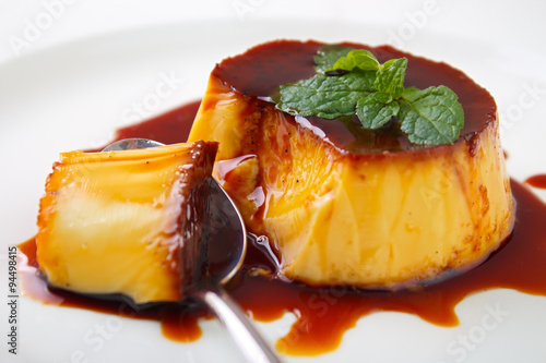 Obraz na płótnie Caramel custard pudding and spoon on plate with lemon balm leave on top w salonie